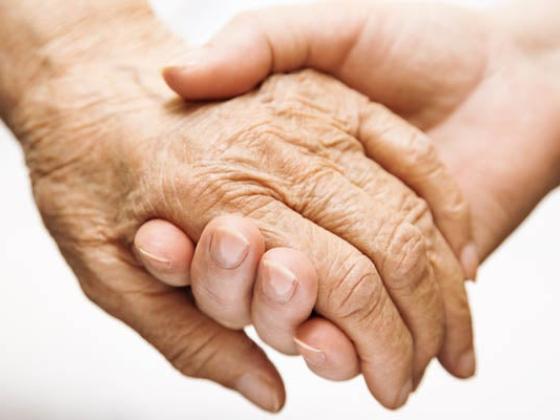 A young hand holding an elderly hand.
