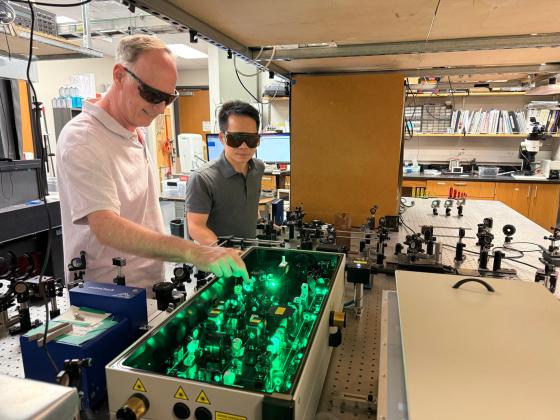 A pair of researchers work in their lab wearing protective goggles.