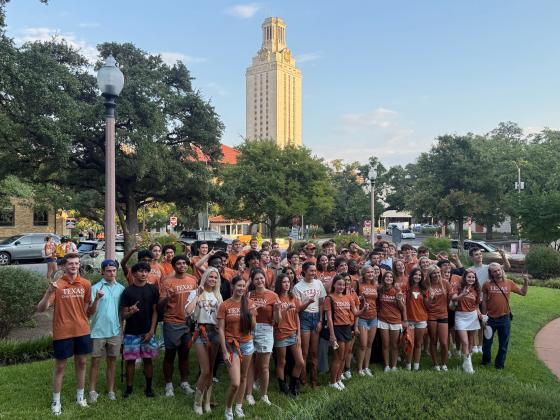 Students in orange T-shirts with the UT Tower in the background