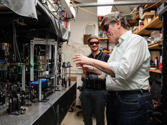 A pair of researchers work in their lab wearing protective glasses.