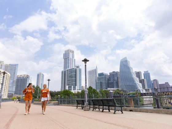 Two students walking on a pedestrian bridge in downtown Austin.