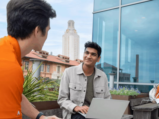 Students talking on a balcony overlooking the University of Texas at Austin Tower.