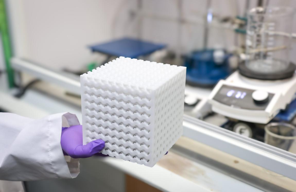A researcher holds a 3D-printed porous cartridge used to filter materials.