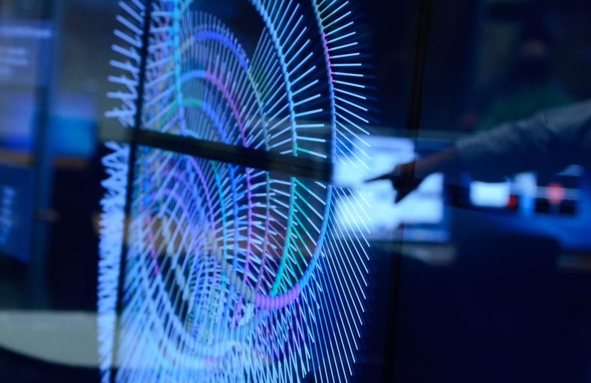 A hand pointing to data visualization on a large touch screen.