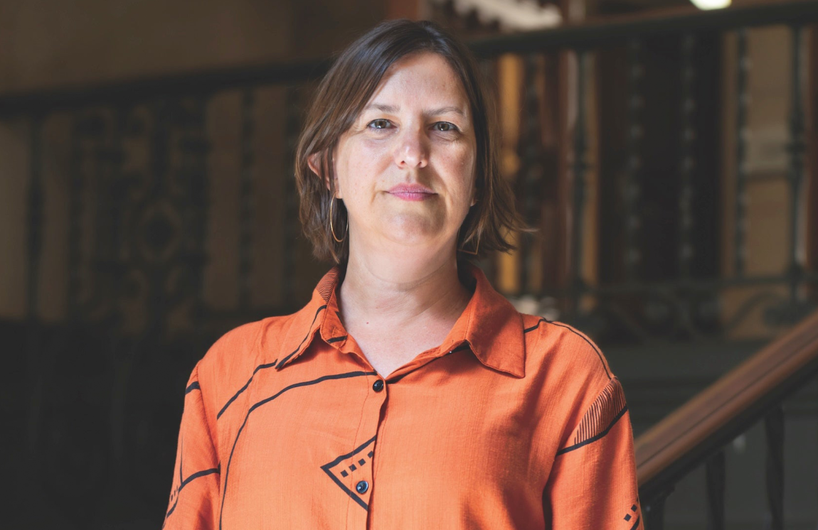 Kim Barker stands on a staircase inside UT's Main Building.