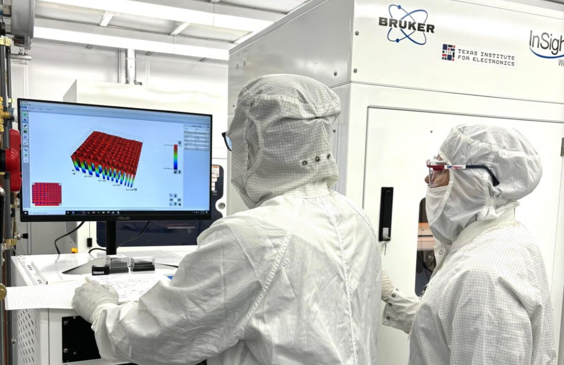 Two researchers in PPE work on a computer in a lab.
