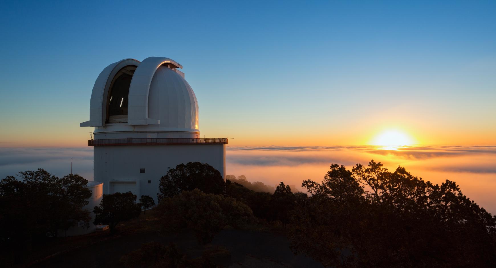 The Sun rises behind the open dome of the Harlan J. Smith Telescope