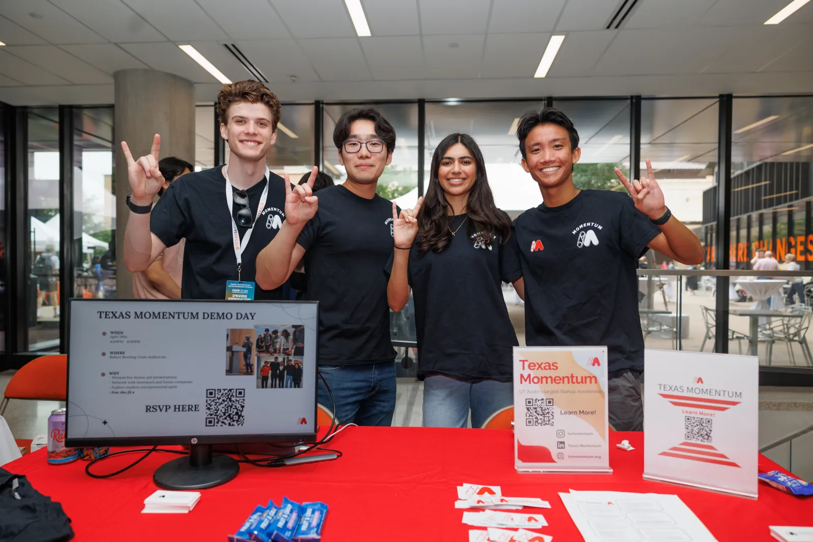 Four students posing for a photo holding up the hook 'em hand sign