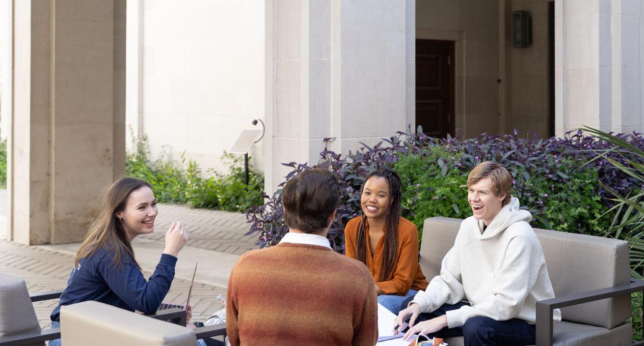 Four UT Law students talking and an outdoor table
