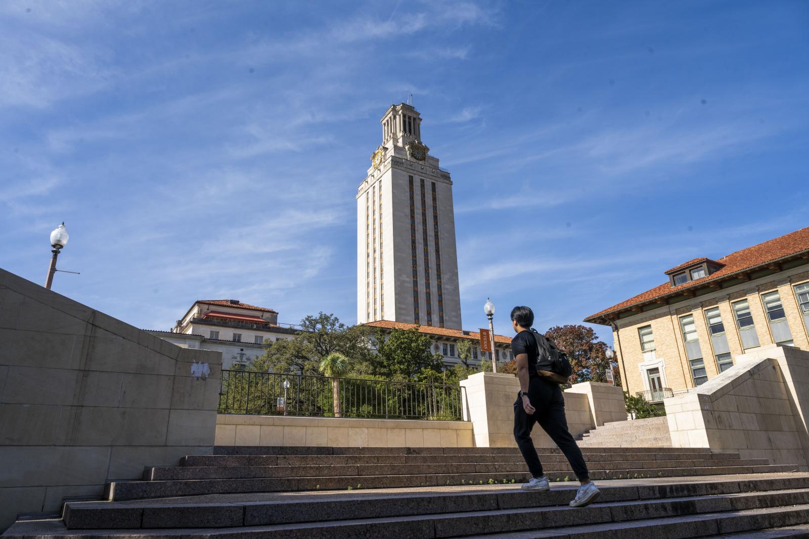 A student walks up the stairs on the east side of the University of Texas at Austin Tower