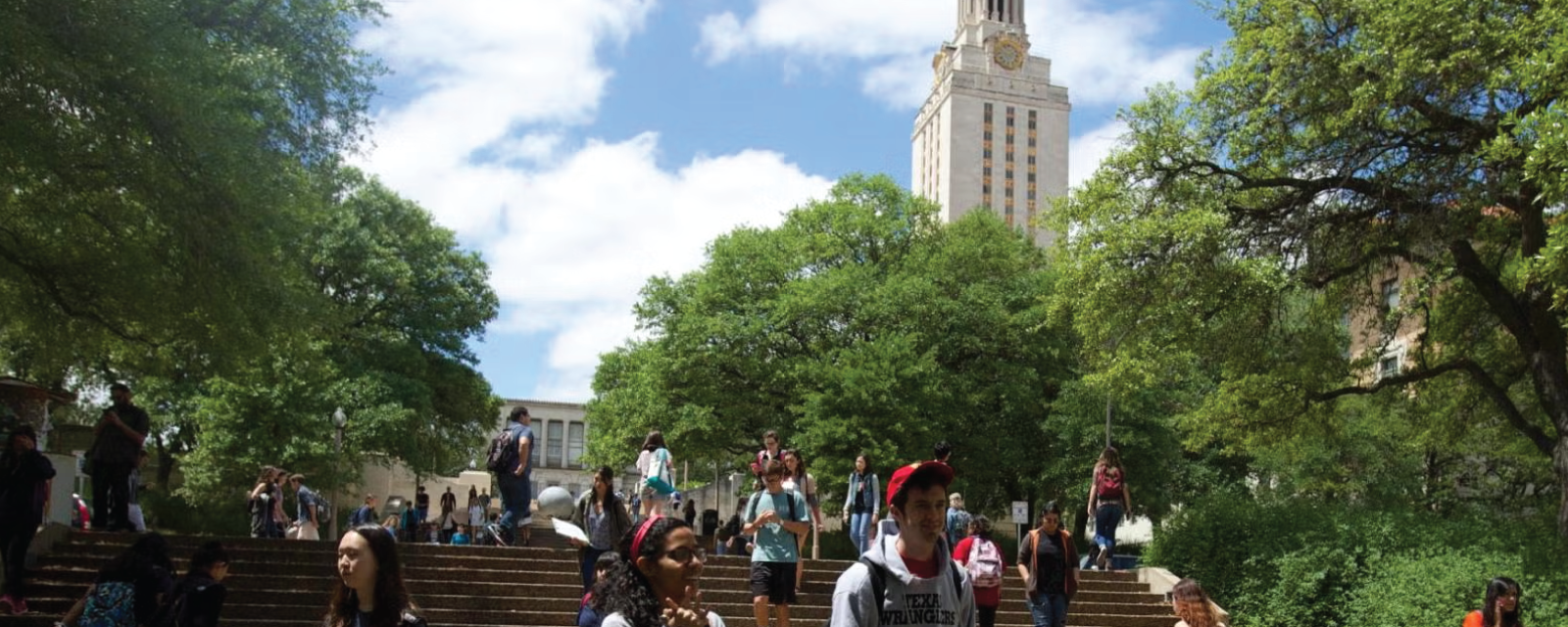 students walking down stairs in front of ut tower and surrounding trees
