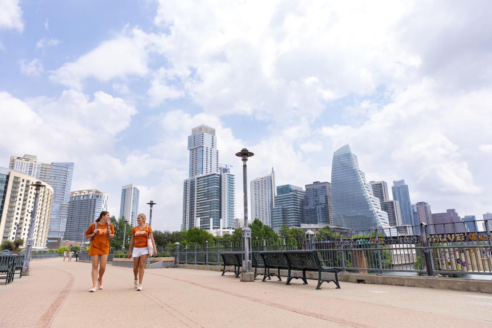 Two students walk across a pedestrian bridge in downtown Austin, Texas.