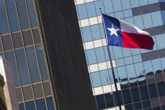 Close-up of donwtown building glass windows and texas flag in foreground