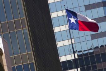 Close-up of donwtown building glass windows and texas flag in foreground