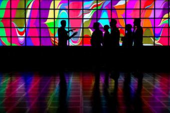 Group of people in front of a wall of screens displaying a colorful pattern