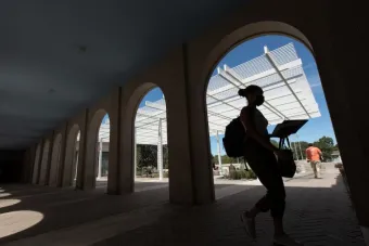 student walking in a portico at the UT Law School