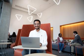 A student smiles while working on a laptop.