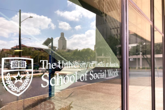 The entrance to The University of Texas at Austin's School of Social Work with the UT Tower reflected in the window.