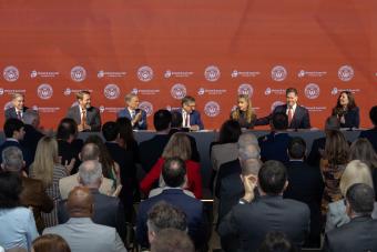 Audience applauds speakers at a press conference.
