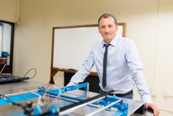A man stands behind a piece of equipment on a table in a lab.