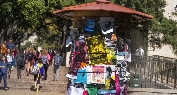 A large bulletin board is covered with brightly colored flyers for different student events. A bright yellow one at the front advertises a screening of The Book of Life, and the pink one below is for a hip-hop group.