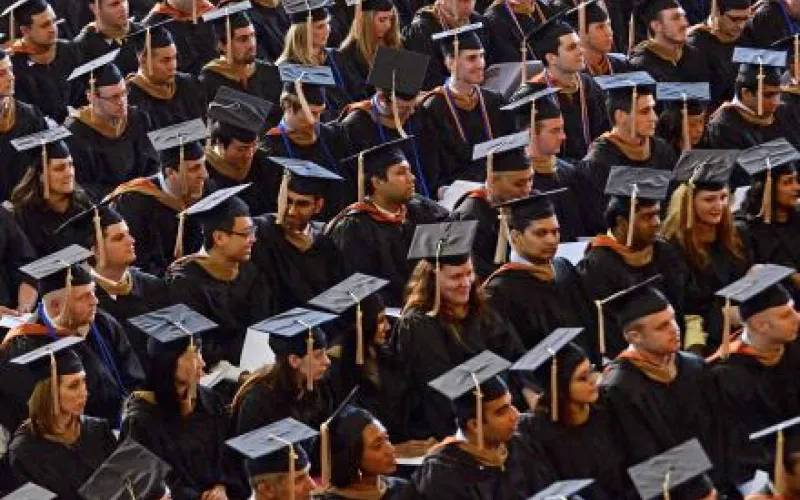 Show of graduates wearing their cap and gowns while they sit at a graduation commencement.