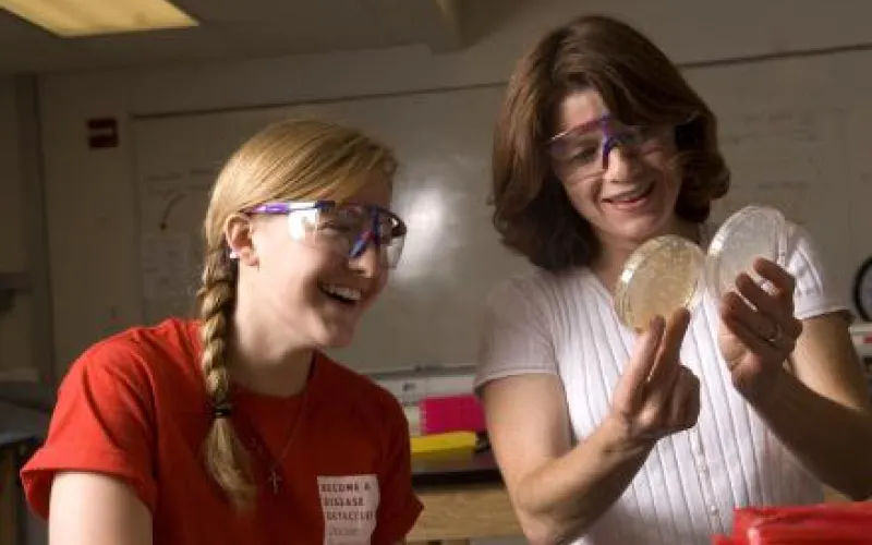 Two girls look at petri dishes together.