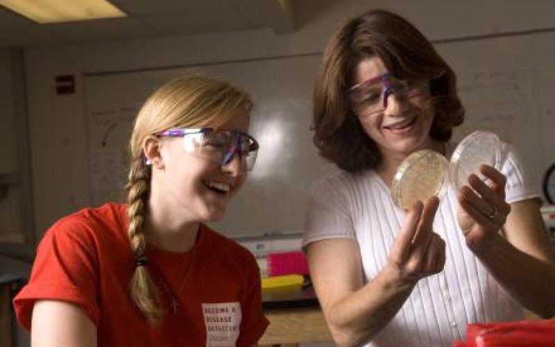 Two girls look at petri dishes together.