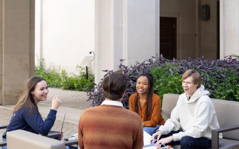 Four UT Law students talking and an outdoor table