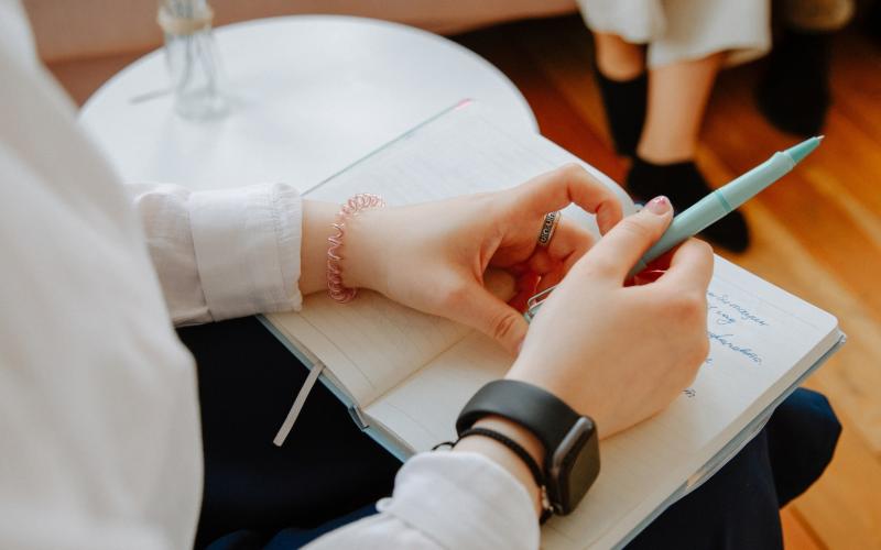 Student in classroom holding pen and notebook