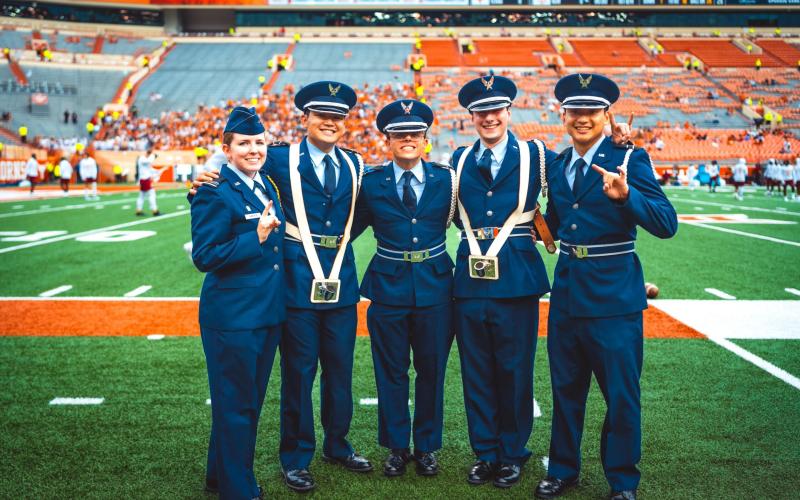 Five U.S. Air Force members posing for a photo on a football field.