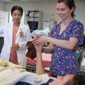 Nursing students receive instruction while helping a patient.