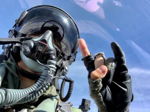 Naval pilot holding up hook &#039;em horn gesture in plane